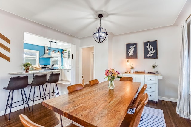 dining room with a notable chandelier, dark wood-style floors, and baseboards