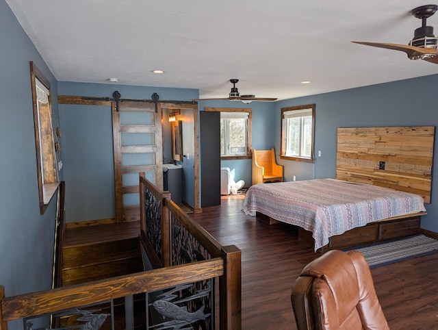 bedroom featuring a barn door, baseboards, and wood finished floors