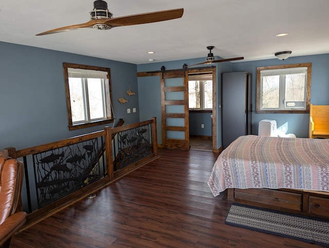 bedroom featuring a barn door, multiple windows, and wood finished floors