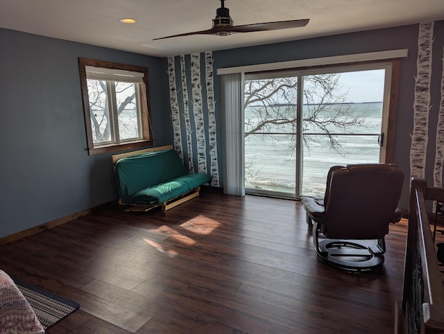 living area featuring wood finished floors, baseboards, and ceiling fan