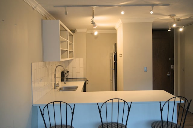 kitchen featuring open shelves, freestanding refrigerator, ornamental molding, a sink, and tasteful backsplash