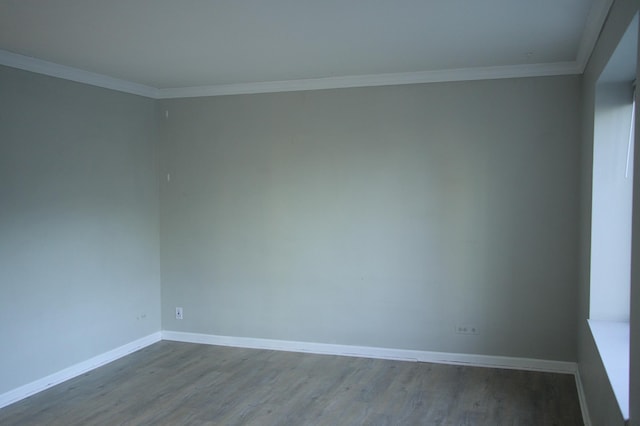 unfurnished room featuring baseboards, wood finished floors, and ornamental molding