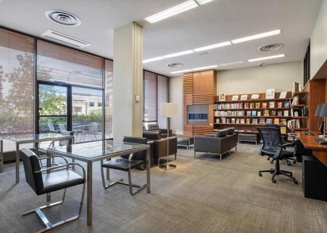 home office with carpet flooring, floor to ceiling windows, and visible vents