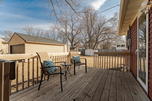 wooden terrace featuring an outdoor structure, a storage unit, fence, and a garage