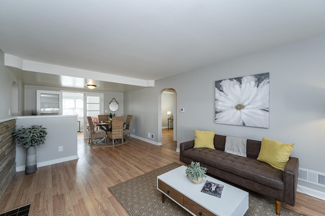 living room featuring visible vents, wood finished floors, and arched walkways