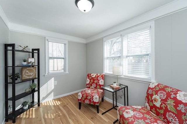 living area with crown molding, wood finished floors, and baseboards