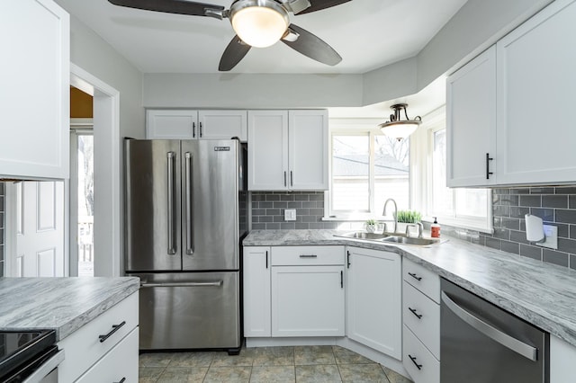 kitchen with a sink, backsplash, appliances with stainless steel finishes, and white cabinets