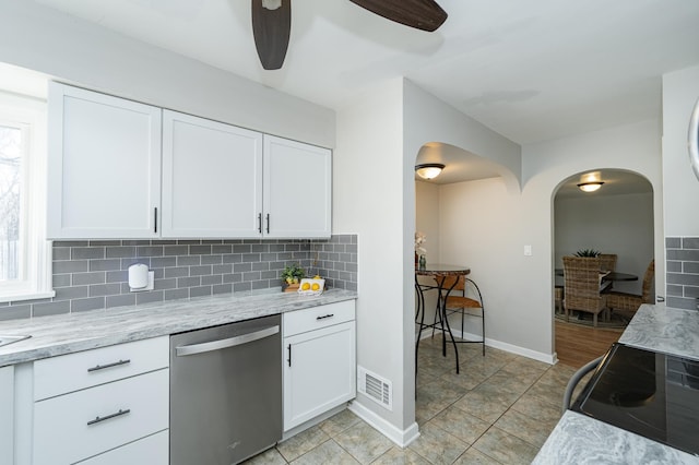 kitchen with visible vents, white cabinetry, arched walkways, stainless steel dishwasher, and backsplash