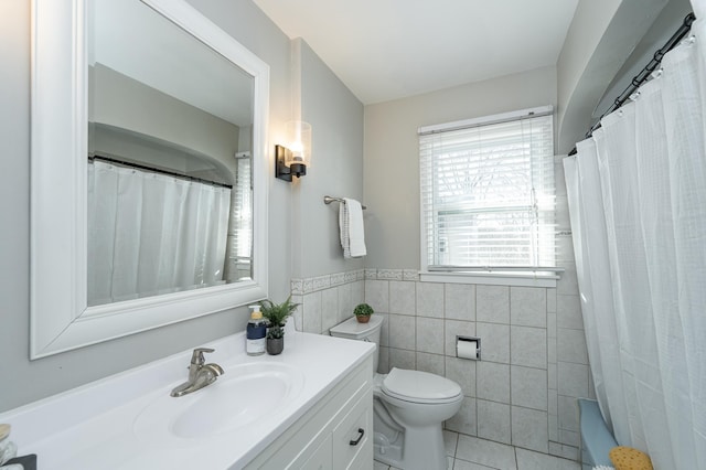 bathroom featuring vanity, wainscoting, tile walls, toilet, and tile patterned floors