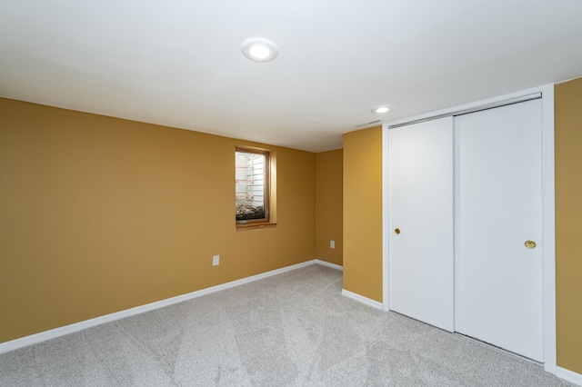 unfurnished bedroom with recessed lighting, light colored carpet, a closet, and baseboards