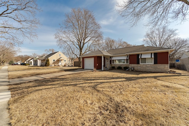 single story home with stone siding, a front lawn, concrete driveway, and a garage