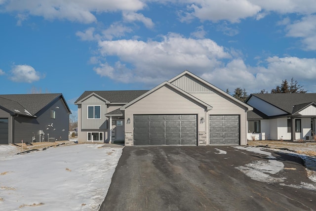 view of front facade featuring aphalt driveway, stone siding, a garage, and board and batten siding