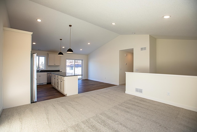 kitchen with vaulted ceiling, dark countertops, dark carpet, and stainless steel appliances