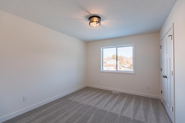 unfurnished bedroom with visible vents, baseboards, carpet floors, and a textured ceiling