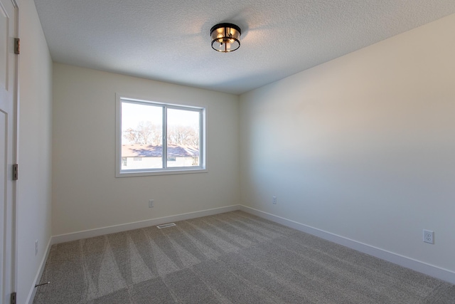 carpeted empty room with visible vents, baseboards, and a textured ceiling