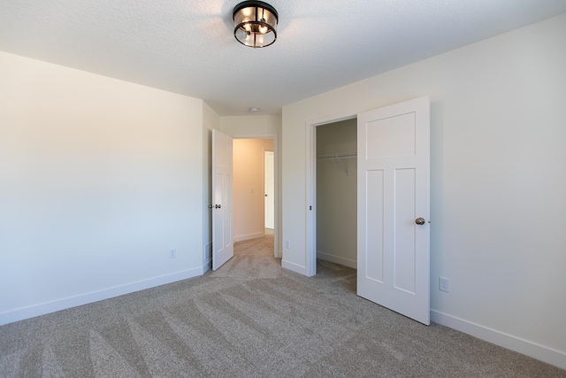 unfurnished bedroom with a closet, baseboards, a textured ceiling, and carpet flooring