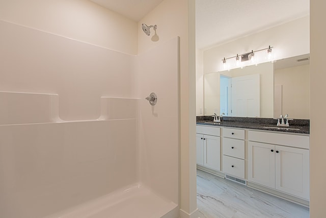 full bath with double vanity, visible vents, a shower, and a sink