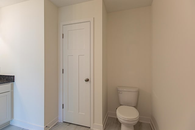 bathroom featuring baseboards, toilet, and vanity