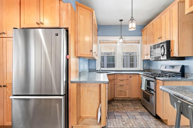 kitchen with a sink, stainless steel appliances, light brown cabinetry, and hanging light fixtures