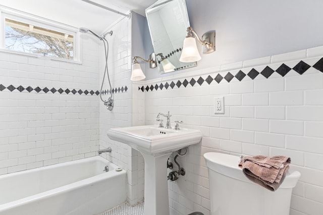 bathroom with wainscoting, toilet, tub / shower combination, and tile walls