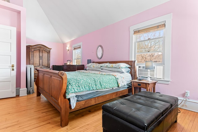 bedroom with cooling unit, light wood-style floors, and high vaulted ceiling