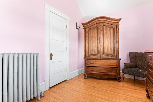 interior space with baseboards, radiator, and light wood finished floors