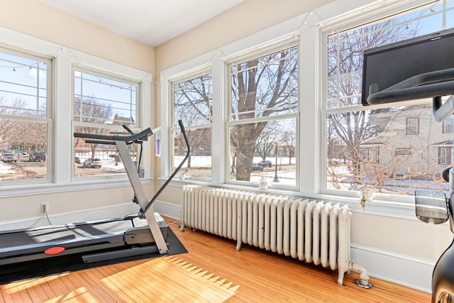 workout room with radiator heating unit, baseboards, and light wood finished floors