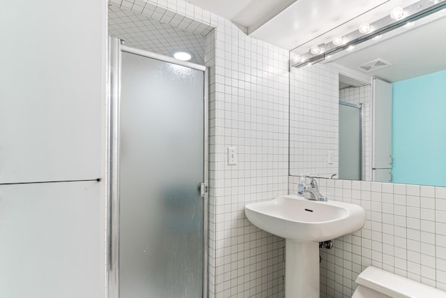 bathroom featuring visible vents, toilet, tile walls, and a stall shower