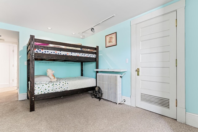 carpeted bedroom with track lighting and radiator heating unit