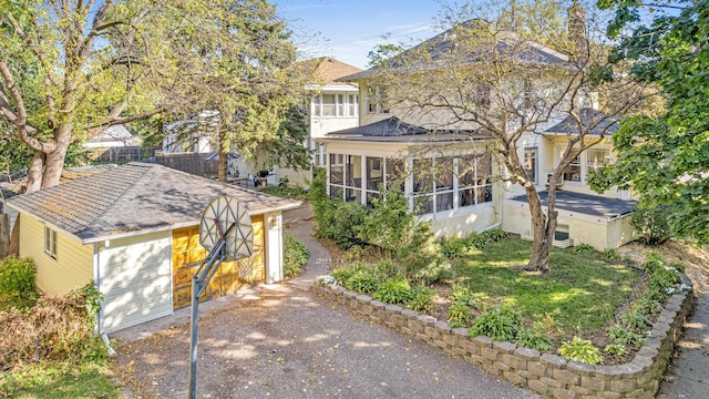 view of front of property featuring a garage, fence, a shingled roof, and a sunroom