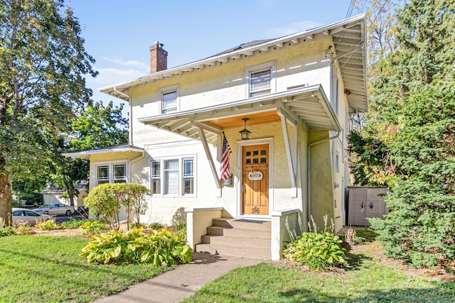 view of front of home with stucco siding, a front lawn, and a chimney