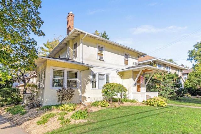 view of front of home with stucco siding, a front yard, and a chimney