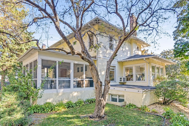 back of house with stucco siding, a lawn, a chimney, and a sunroom