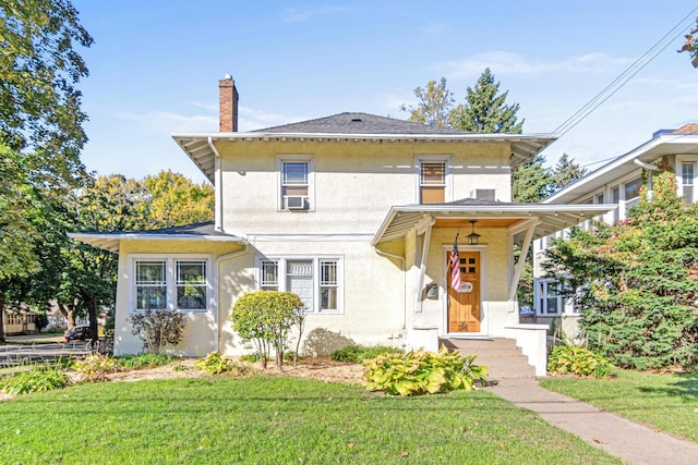 american foursquare style home with stucco siding, a chimney, cooling unit, and a front yard