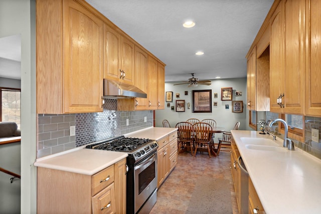 kitchen featuring tasteful backsplash, under cabinet range hood, light countertops, appliances with stainless steel finishes, and a sink