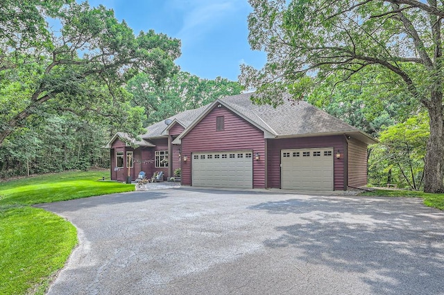 view of front of home featuring a shingled roof, a front lawn, a garage, and aphalt driveway