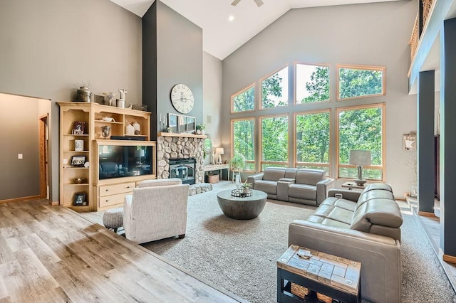 living area with baseboards, high vaulted ceiling, wood finished floors, and a fireplace