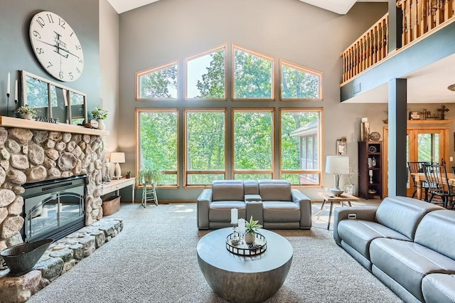 carpeted living area featuring a wealth of natural light, a high ceiling, and a fireplace