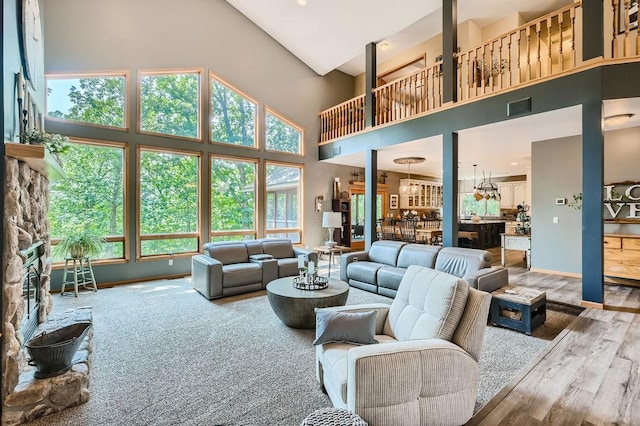 living area with visible vents, wood finished floors, baseboards, and a towering ceiling