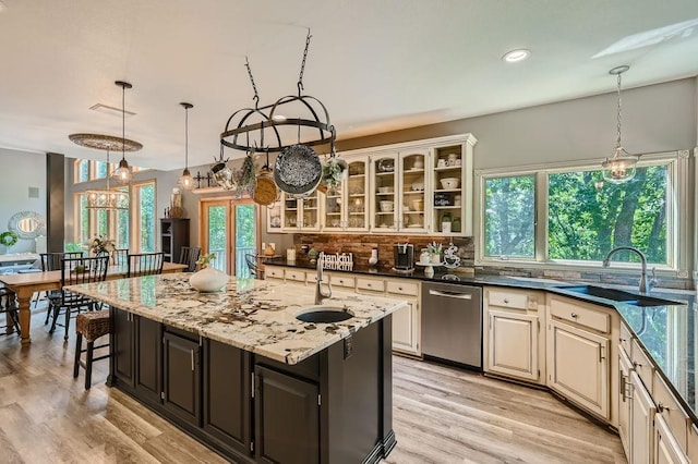 kitchen with light wood-style flooring, a sink, decorative backsplash, dishwasher, and cream cabinets