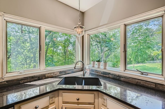 kitchen with dark stone counters, pendant lighting, and a sink