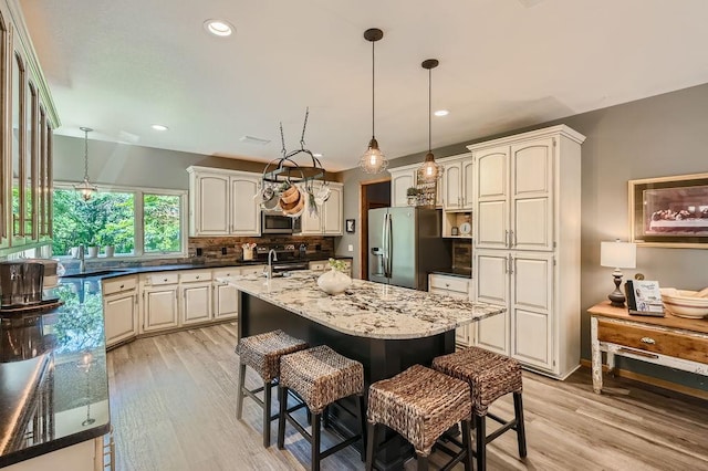 kitchen with a breakfast bar area, light wood-type flooring, decorative backsplash, stainless steel appliances, and a sink