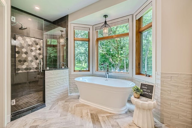 full bathroom featuring a shower stall, a freestanding tub, and tile walls