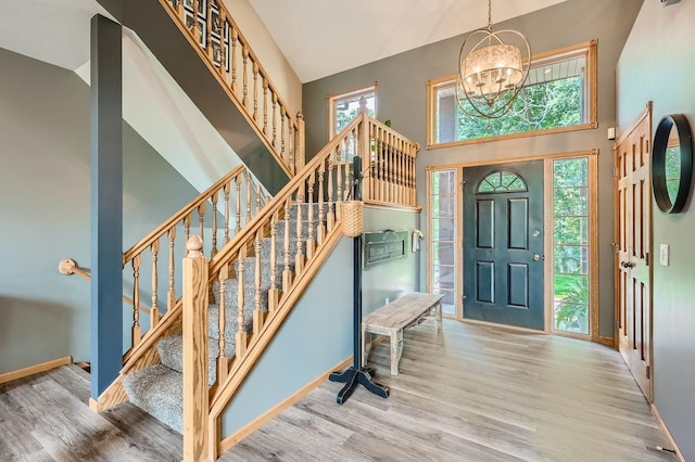 entrance foyer featuring stairway, a high ceiling, a notable chandelier, and wood finished floors