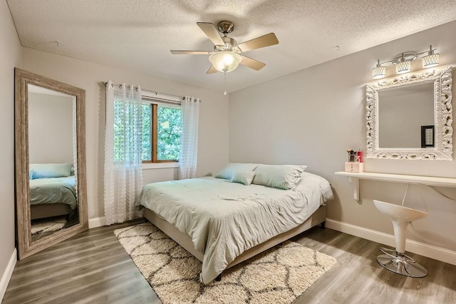 bedroom featuring ceiling fan, wood finished floors, baseboards, and a textured ceiling