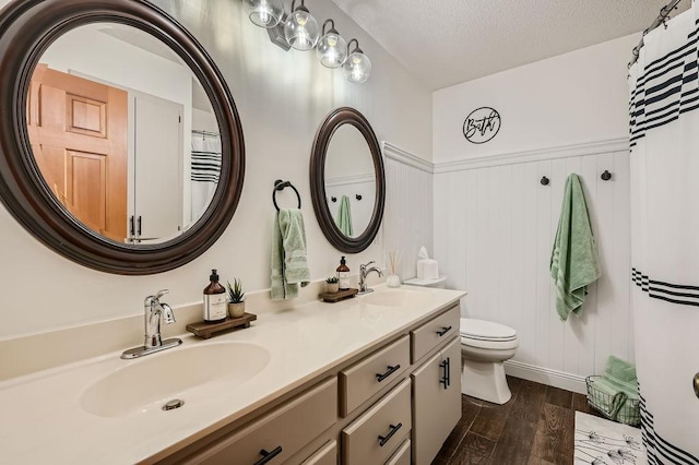 full bath with a sink, a textured ceiling, wood finished floors, and double vanity