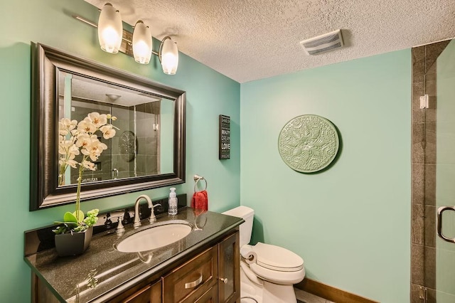 bathroom with vanity, visible vents, tiled shower, a textured ceiling, and toilet