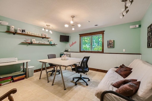 office area featuring a textured ceiling, a notable chandelier, rail lighting, and wainscoting