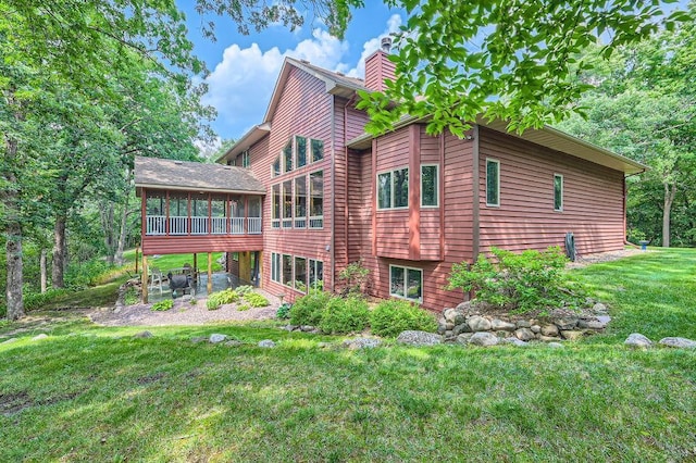 back of property featuring a lawn, a sunroom, and a chimney