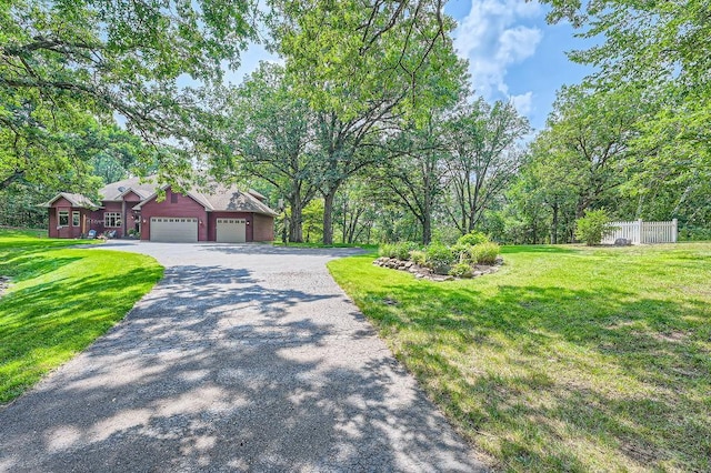 exterior space featuring a front lawn, an attached garage, fence, and driveway